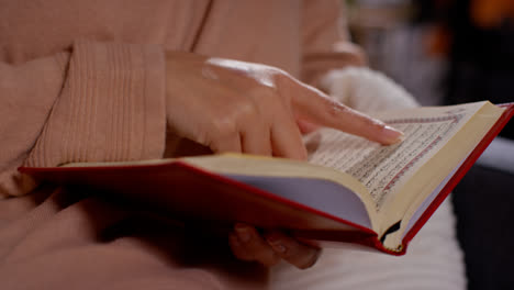 Close-Up-Of-Muslim-Woman-Sitting-On-Sofa-At-Home-Reading-Or-Studying-The-Quran-7